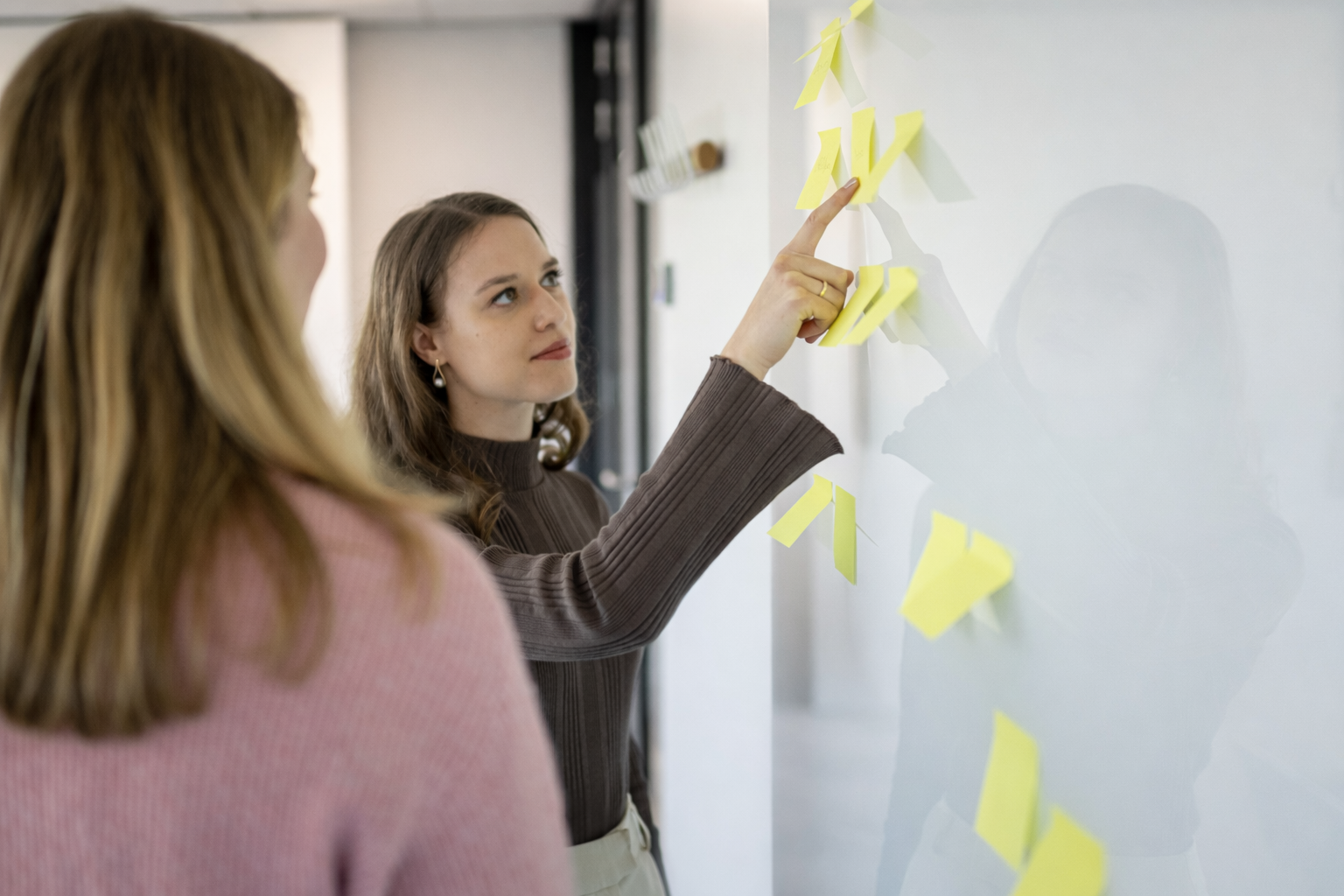 Collega’s werken een preventieplan uit met post-its op een glazen wand.